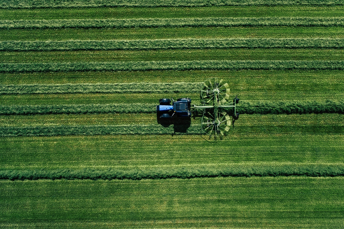 blue-tractor-mowing-green-field-1200-800-min